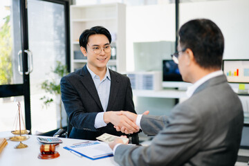 Lawyer and client shaking hands after contract signing with money and gavel on desk. Ideal for business, finance, partnership, or legal themes.