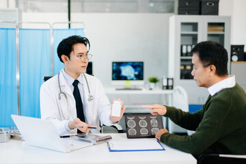 Obraz premium Doctor discussing brain MRI results and medication with patient during medical consultation. Perfect for healthcare, diagnosis
