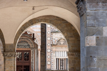 Obraz premium View of the Colleoni Chapel from the arches of Palazzo della Ragione in Bergamo Lombardy, Renaissance marble facade with portal rose window and reliefs framed by ancient stone vaults
