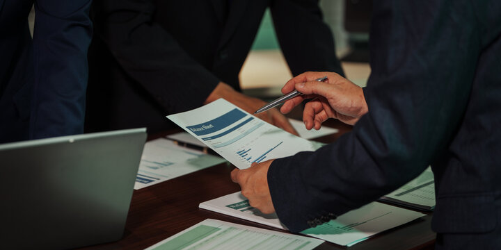 Business professionals closely review a balance sheet and digital Global Investment Portfolio data, pointing to key figures, indicating strategic financial planning and rigorous cash flow management.