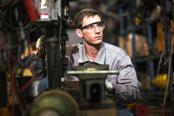 White man technician checking used car damaged engine block at scrap yard warehouse recycle area part. Maintenance engineer inspecting rust oily auto motor old spare part in junkyard for reuse service