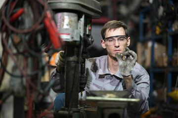 White man technician checking used car damaged engine block at scrap yard warehouse recycle area part. Maintenance engineer inspecting rust oily auto motor old spare part in junkyard for reuse service