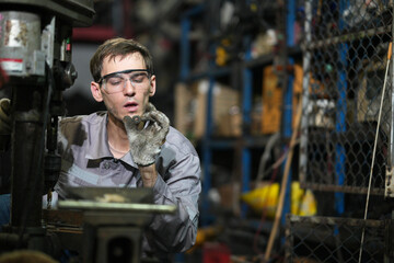 White man technician checking used car damaged engine block at scrap yard warehouse recycle area part. Maintenance engineer inspecting rust oily auto motor old spare part in junkyard for reuse service
