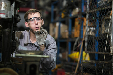 White man technician checking used car damaged engine block at scrap yard warehouse recycle area part. Maintenance engineer inspecting rust oily auto motor old spare part in junkyard for reuse service