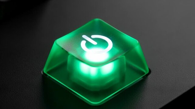 Macro shot of glowing green power button keycap on a black surface power on concept