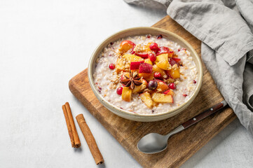  Overnight oatmeal with apple, cranberry and cinnamon in a bowl on a wooden board on a light background