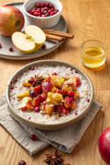  Overnight oatmeal with apple, cranberry and cinnamon in a plate on a wooden background with honey, spice and fruit.