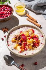 Overnight oatmeal with apple, cranberry, honey and cinnamon in a plate on a light background