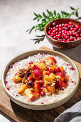 Overnight oatmeal with apple, cranberry and cinnamon in a plate on a wooden board on a light background