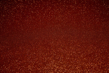 Dark red glitter background with sharp focus in central area, golden sparkles scattered across surface create elegant shimmering effect