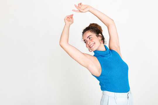 Happy beautiful woman with arms raised standing against white background