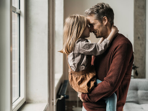 Father and daughter rubbing noses at home