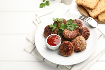 Delicious patties with parsley, ketchup and fork on white wooden table, closeup. Space for text