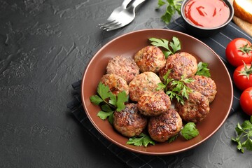 Delicious patties with parsley in bowl, tomatoes and ketchup on dark textured table, closeup. Space for text