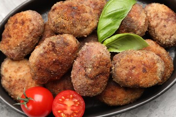Tasty meat patties with basil and tomatoes on grey table, top view