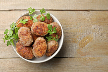 Tasty meat patties with parsley o wooden table, top view. Space for text