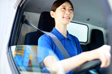 トラックを運転する女性ドライバー　配送　物流　配達