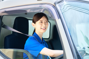 トラックを運転する笑顔の女性ドライバー　配送　運送