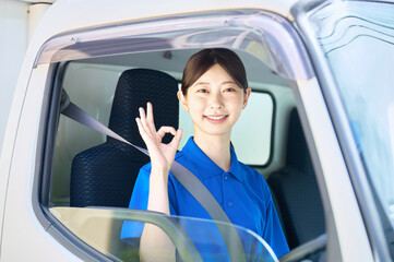 トラックを運転するOKサインの女性ドライバー
