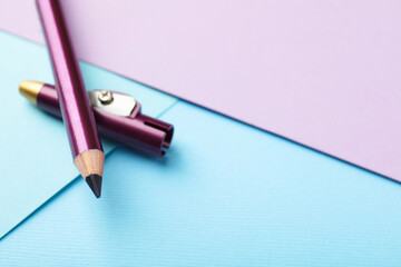 Eye pencil with sharpener on color background, closeup. Space for text