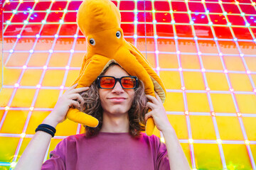 Teenager at amusement park with octopus toy hat under neon lights