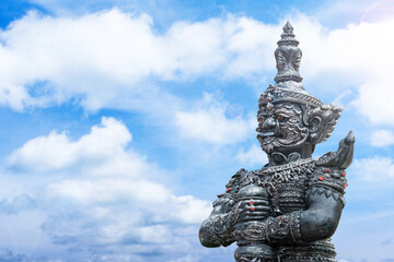 Fototapeta premium Thao Wessuwan statue of a demon guardian, stands sentinel against a backdrop of a bright blue sky