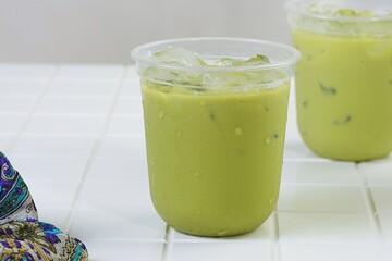 Two cups of iced matcha green tea with creamy texture on bright white background, ideal for summer beverage and lifestyle content