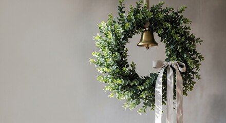 Green wreath with bell and ribbon on a plain neutral wall