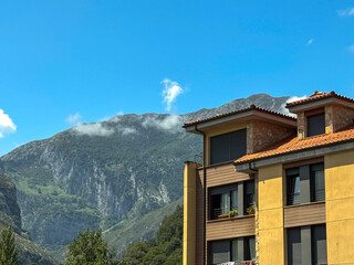 Modern apartment building against mountain landscape on sunny day