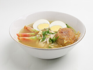 Soto Ayam or chicken soup cooked in chicken broth served with boiled egg, shredded chicken, bean sprout, fried mashed potato
