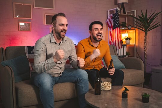 Excitement fills the room as two friends cheer for their team during a thrilling sports event night - Powered by Adobe