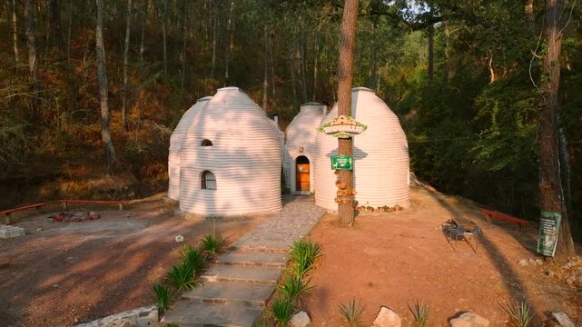 Round superadobe dome structures with small windows in wooded eco park setting in Tapalpa, Mexico