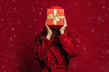 Woman in red coat holding Christmas gift box in snowy festive mood