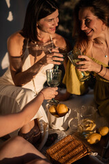 Three young women enjoying a cozy picnic together, surrounded by fresh lemons. Warm summer light, relaxed atmosphere and bright yellow accents create a cheerful, natural lifestyle scene.