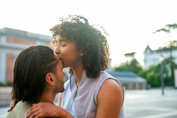Interracial couple sharing tender kiss outdoors