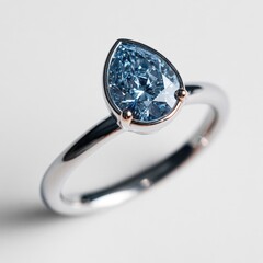 Stunning close-up of a pear-shaped fancy blue diamond set in a contemporary white gold or platinum band with rose gold accents on the prongs, emphasizing the brilliant cut and color