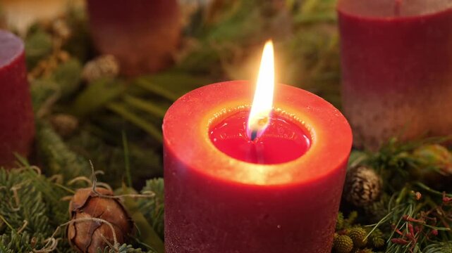 Lit red candle with pine cones and foliage, festive detail