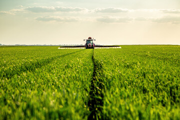 Tractor spraying crops in green agricultural field