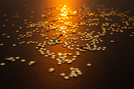 &Eacute;toiles dor&eacute;es brillantes sur un fond brun avec un rayon lumineux dor&eacute; central, ambiance festive de No&euml;l et de f&ecirc;tes de fin d'ann&eacute;e