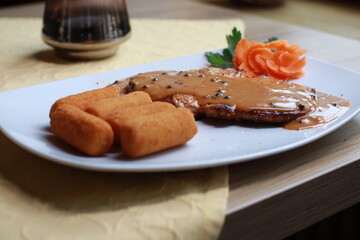 Schnitzel mit schwarzer Pfeffersoße Kroketten und Tellerdeko schön angerichtet