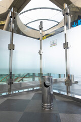 Airport smoking zone enclosed by glass walls in a corner section of the terminal, providing a designated area for passengers to smoke.