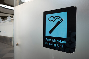 Smoking area sign displayed inside a modern glass enclosure with a blue icon, indicating a designated smoking zone in a public space.