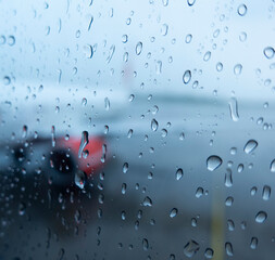 Rain on Window View at Airport With Blurred Airplane and Wet Runway