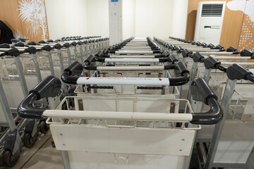 A row of airport luggage trolleys with black handles neatly arranged in a line