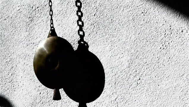 Timeless Shadows: A captivating monochrome image showcases a pendulum clock, its metallic forms and delicate chain casting elongated shadows, creating a serene and timeless composition. 