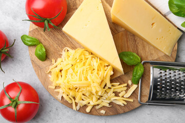 Grater, tomatoes, basil, grated and pieces of cheese on light table, closeup