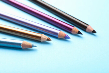 Eye pencils on light blue background, closeup