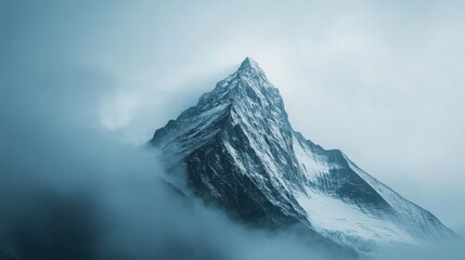 Majestic snow-capped mountain peak rising through the fog in a tranquil landscape