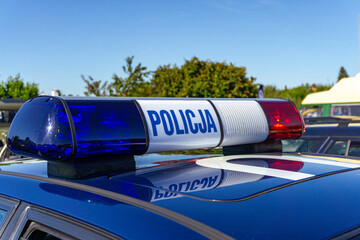 Old light bar with the word "Policja" on the roof of a patrol car during a vintage vehicle rally, historic police car detail © Adam