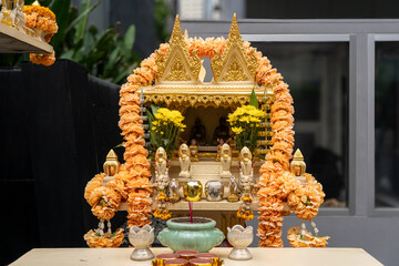 Gold Thai Spirit House with Offerings and Marigold Garlands in Bangkok, Thailand